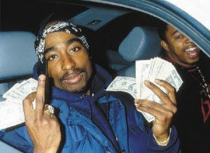 Tupac Shakur holding cash while giving the middle finger